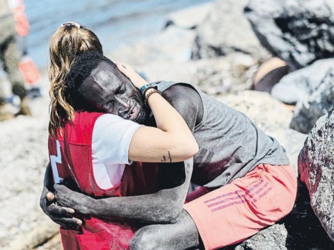 Una voluntaria de Cruz Roja consuela a un migrante que acaba de llegar a Ceuta