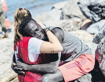 Una voluntaria de Cruz Roja consuela a un migrante que acaba de llegar a Ceuta